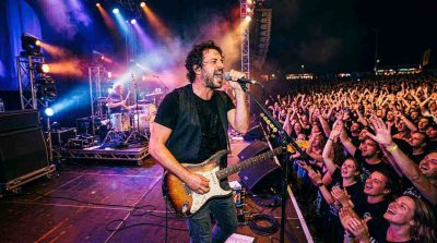 A musician performing energetically on stage in front of an engaged audience